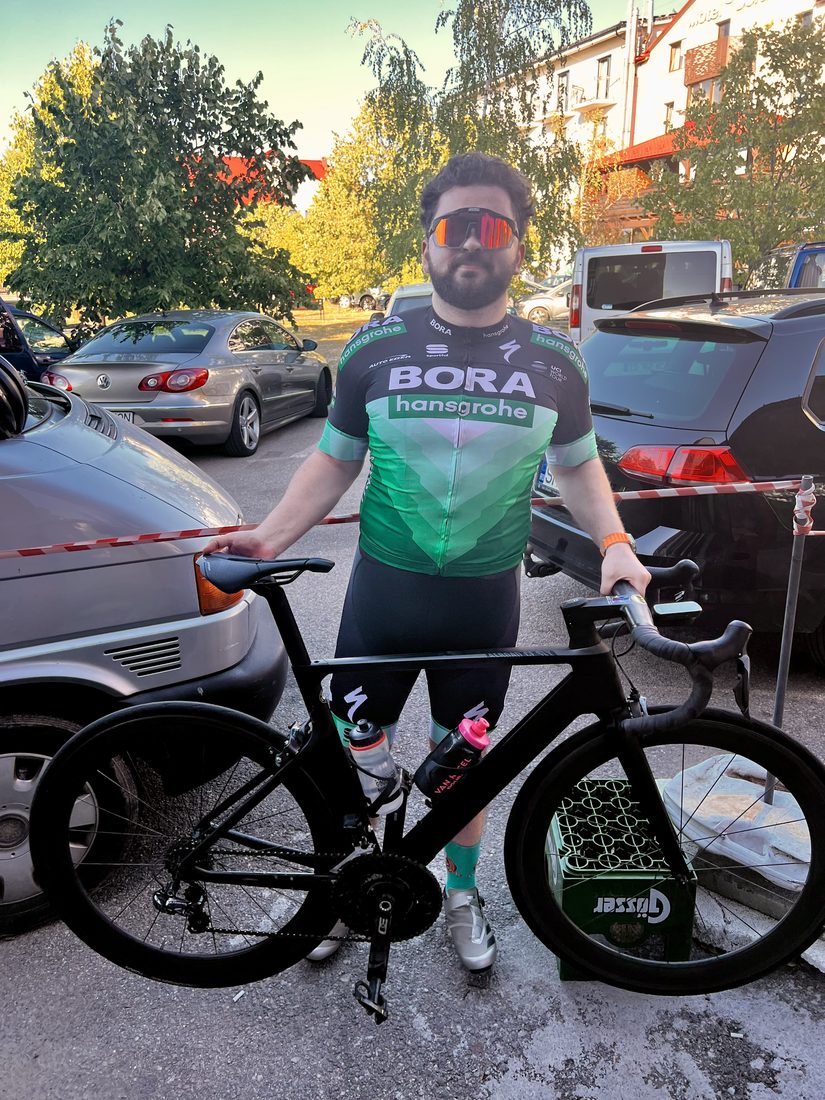 Márk in BORA kit with his black Canyon after a race, a beer crate by the wheel